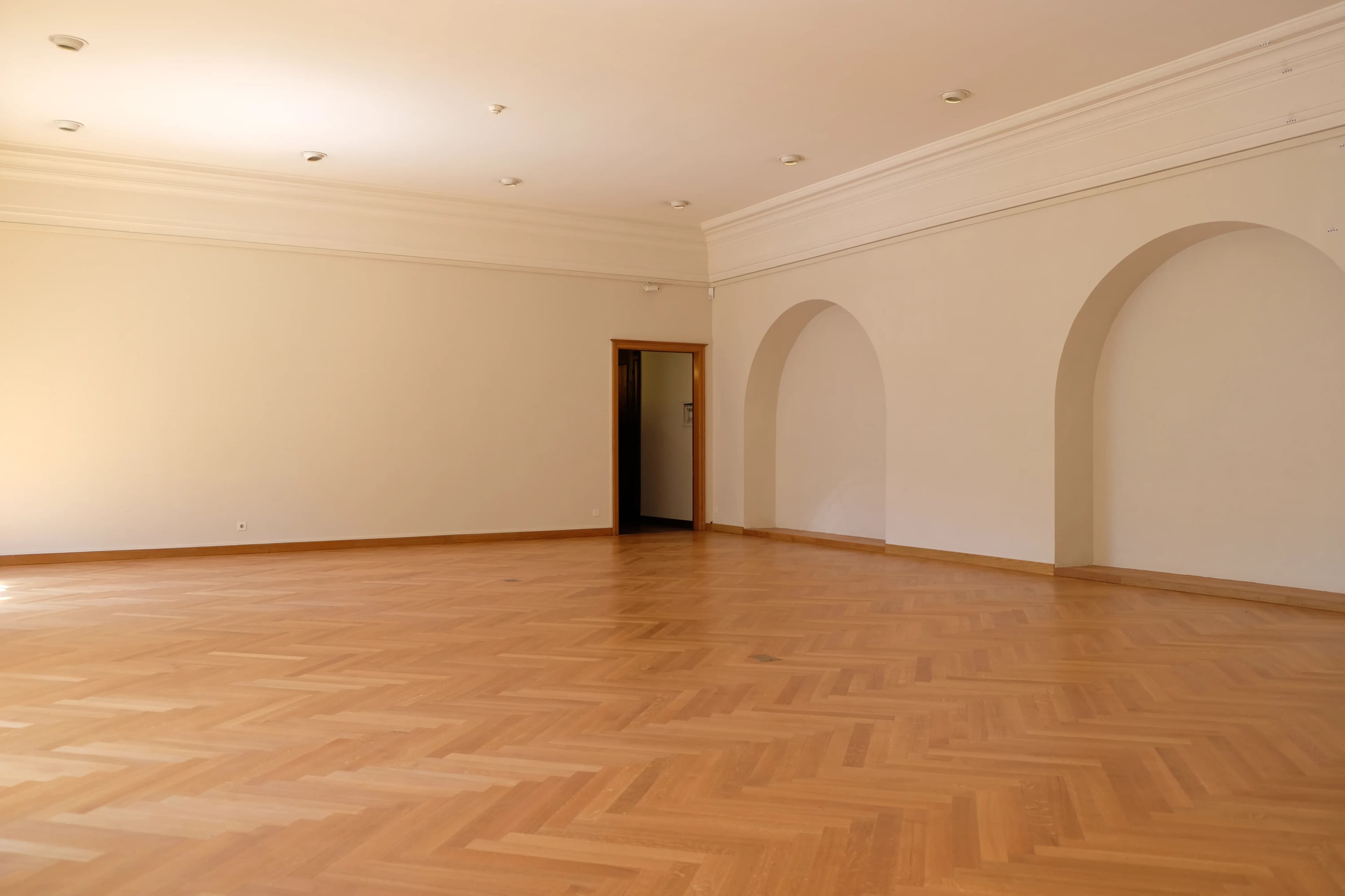 Large sunlit room with wide timber floorboards and arched openings